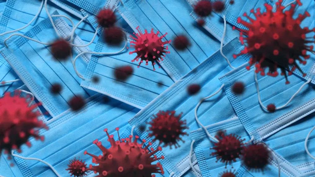 A pile of blue surgical masks is seen in the background, with red virus-like particles floating in the foreground, visually symbolizing the COVID-19 pandemic and highlighting the importance of certified IV nurses and quality IV solutions.